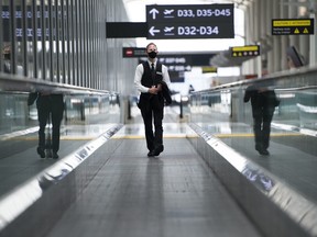 A man rides a escalator wearing mandatory masks at Toronto's Pearson International Airport for a "Healthy Airport" during the COVID-19 pandemic in Toronto, Tuesday, June 23, 2020.
