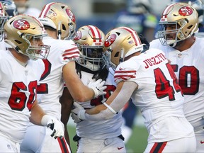 San Francisco 49ers running back JaMycal Hasty, centre, celebrates wth teammates after rushing for a touchdown against Seattle Seahawks defensive tackle Bryan Mone during the second quarter at CenturyLink Field.