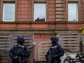 Policemen stand in front of a residential building in Linz, Austria, where a man was detained on Nov. 3, 2020 in connection with the Vienna shooting one day before.