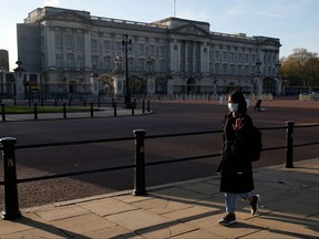 A woman wearing a face mask waves as she walks past Buckingham Palace in central London as England enters a second coronavirus lockdown on November 5, 2020.