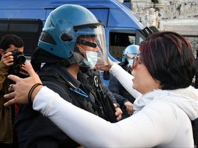 A protester hugs a police officer in provocation on Nov. 15, 2020, in Rome, during a demonstration of anti-mask supporters and against government restrictions over the COVID-19 pandemic, caused by the novel coronavirus.