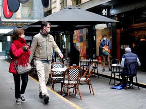 People walk past a cafe after the coronavirus restrictions were eased for the state of Victoria, in Melbourne, Australia, October 28, 2020.