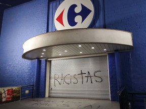 This file photo taken on November 20, 2020 shows graffiti written by demonstrators reading "Racists" at the entrance of a Carrefour supermarket in Curitiba, Brazil.