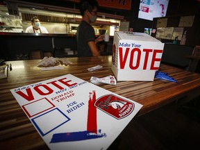 A server collects a food order beside a mock polling station for patrons as they watch U.S. election returns at The Unicorn bar in Calgary on Tuesday, Nov. 3, 2020.
