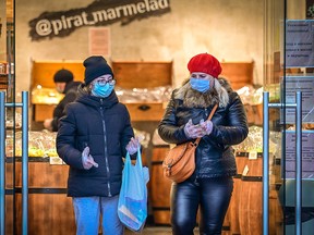Two women wearing masks and gloves as a measure against the spread of the Covid-19  pandemic leave a grocery store in central Moscow on November 8, 2020.