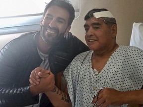 This handout photo taken Nov. 11, 2020 and released by the press officer of Diego Armando Maradona shows Argentine soccer legend Diego Maradona (right) shaking hands with his doctor Leopoldo Luque in Olivos, Argentina.