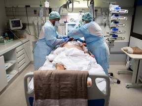Medical personnel attend a COVID-19 patient at the intensive care unit of the clinic of Occitanie in Muret, near Toulouse, France, Monday, Nov. 16, 2020.