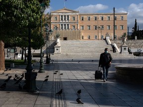 A man wearing a mask makes his way on Syntagma square with the parliament building in the background, after the Greek government imposed a nationwide lockdown to contain the spread of the coronavirus in Athens, Greece, November 9, 2020.