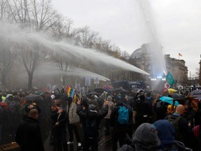 Police use a water cannon to disperse protesters demonstrating against measures imposed by the German government to limit the spread of the novel coronavirus,  close to the Reichstag building housing the Bundestag in Berlin, on Wednesday, Nov. 18, 2020.