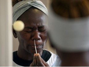 Healthcare assistant Sheba Anyebe is reflected in a bathroom cabinet as she self-administers a rapid coronavirus test which produces a result in thirty minutes at The Chiswick Nursing Centre, following the outbreak of the coronavirus disease (COVID-19) in London, Britain, November 26, 2020.