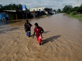 Men walk along a street flooded by the Chamelecon River due to heavy rain caused by Storm Iota, in La Lima, Honduras November 19, 2020.