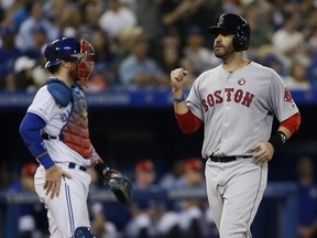 Red Sox left fielder J.D. Martinez (right) reacts after scoring on  a three-run homer by first baseman Michael Chavis (not pictured) as Blue Jays catcher Danny Jansen (left) looks on during MLB action at Rogers Centre in Toronto, July 4, 2019.
