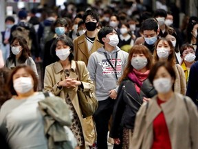 People wearing protective face masks walk on the street, amid the COVID-19 outbreak, in Tokyo, Japan, Thursday, Nov. 19, 2020.