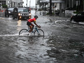 A cyclist rides through the flooded street during heavy rain and wind as tropical storm Eta approaches the south of Florida, in Miami on November 9, 2020.
