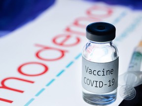 This picture taken on November 18, 2020 shows a syringe and a bottle reading "Vaccine Covid-19" next to the Moderna biotech company logo.