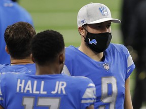 Detroit Lions quarterback Matthew Stafford (9) wears a mask on the sidelines before a game against Washington at Ford Field.