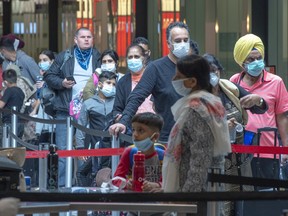 Passengers wear mandatory face masks as they wait to go through security at Trudeau Airport, Wednesday, April 22, 2020 in Montreal.