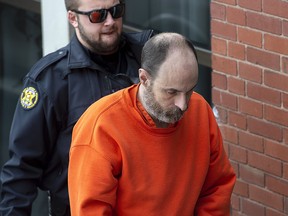 Matthew Raymond is escorted at Court of Queen's Bench in Fredericton on Wednesday, Dec. 18, 2019.