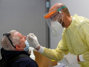 A health worker takes a swab sample from a man to test for the coronavirus at the Fiumicino Airport in Rome, Italy, September 23, 2020.