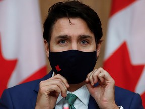 Prime Minister Justin Trudeau puts on a mask at a news conference held to discuss the country's coronavirus response in Ottawa November 6, 2020.
