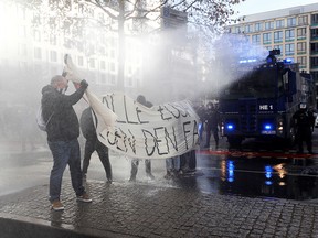 Police officers use a water cannon against left-wing demonstrators standing on a road to stop the protest against the government's restrictions in Frankfurt, Germany, November 14, 2020.