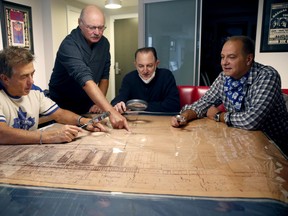 Mike Wilson (left) surveys blueprints from the old Maple Leaf Gardens with a group of men.