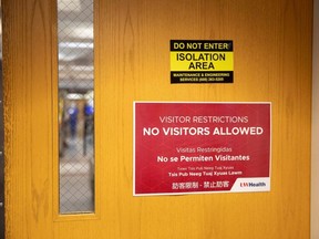 Signage hangs on entry doors to a hospital wing housing COVID-19 patients at UW Health University Hospital in Madison, Wis., Wednesday, Nov. 18, 2020.