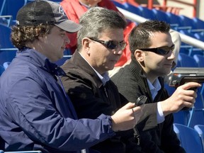 Toronto Blue Jays scouts Tony LaCava (C) and Perry Minasian (L) work the radar gun for General Manager Alex Anthopoulos (R) at the Blue Jays Spring Training stadium in Dunedin Florida.