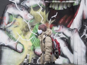 A person wears a face mask as they walk by a mural in Montreal, Sunday, November 15, 2020, as the COVID-19 pandemic continues in Canada and around the world.