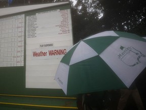 Golf - The Masters - Augusta National Golf Club - Augusta, Georgia, U.S. - November 12, 2020 A umbrella is pictured next to the scoreboard stating 'Weather warning' after play was suspended during the first round.