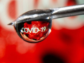 The word "COVID-19" is reflected in a drop on a syringe needle in this illustration taken Nov. 9, 2020.