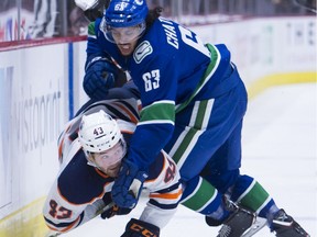 Canucks defenceman Jalen Chatfield puts Edmonton Oilers right-winger Josh Currie into the boards during pre-season action in Vancouver last year.