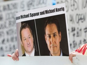 In this file photo taken May 8, 2019, Turnisa Matsedik-Qira, of the Vancouver Uyghur Association, demonstrates against China's treatment of Uighurs while holding a photo of detained Canadians Michael Spavor (left) and Michael Kovrig (right) outside a court appearance for Huawei Chief Financial Officer Meng Wanzhou, at the B.C. Supreme Court in Vancouver.