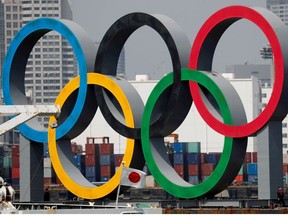 The giant Olympic rings are seen behind Japan's national flag amid the coronavirus disease (COVID-19) outbreak, at the waterfront area at Odaiba Marine Park in Tokyo, Japan August 6, 2020.