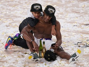 Los Angeles Lakers' Rajon Rondo sits in the confetti with his son Rajon Jr. after the Lakers defeated the Miami Heat 106-93 in Game 6 of the NBA Finals, Sunday, Oct. 11, 2020, in Lake Buena Vista, Fla.