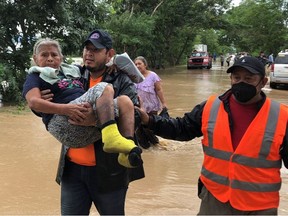Members of the Honduras Permanent Contingencies Commission (COPECO) rescue a woman from her flooded home after the passage of Storm Eta, in El Progreso, Honduras November 6, 2020.