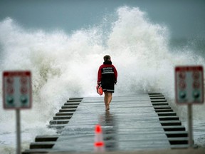 A lifeguard walks to the end of the pier after closing it down to surfers before the arrival of Tropical Storm Eta in Bradenton Beach, Fla., Nov. 11, 2020.