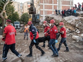 Emergency personnel carry a dead body Sunday, Nov. 1, 2020, as they work in a collapsed building after a powerful earthquake struck two days earlier in Izmir, Turkey.