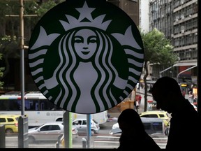 Customers pass by the logo of an American coffee company Starbucks inside a coffee shop in Rio de Janeiro, Brazil August 15, 2018.