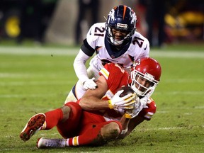 Travis Kelce of the Kansas City Chiefs controls the ball ahead of A.J. Bouye of the Denver Broncos during the fourth quarter of a game at Arrowhead Stadium on December 06, 2020 in Kansas City, Missouri.
