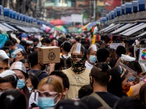 Filipinos wearing masks and face shields for protection against COVID-19 walk along a street market in Manila, Philippines, Dec. 3, 2020.