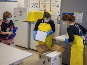 Health-care workers unpack a shipment of Pfizer/BioNTEch COVID-19 vaccines to the CHSLD St-Antoine long term care home in Quebec City, Dec. 14, 2020.