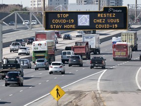Traffic on Highway 401 in Toronto passes under a COVID-19 sign on Monday April 6, 2020.