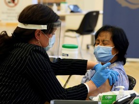 A health-care worker administers a Pfizer/BioNTEch COVID-19 vaccine to personal support worker Anita Quidangen at The Michener Institute, in Toronto, Dec. 14, 2020.