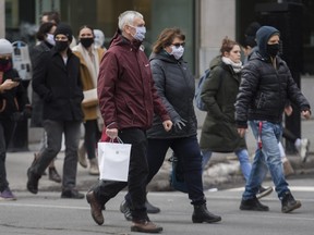 People wear face masks as they walk along a street in Montreal, Sunday, Nov. 29, 2020, as the COVID-19 pandemic continues in Canada and around the world.