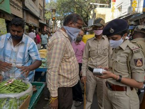 Police personal impose a fine to a man (centre) who was not wearing a face mask during an enforcement drive in Bangalore, India, Dec. 1, 2020.