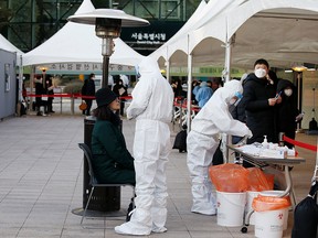 A woman undergoes a test for COVID-19 at a temporary site set up at City Hall Plaza in Seoul, South Korea December 18, 2020.