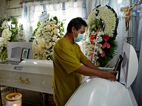 Florentino Gregorio stands beside the coffin of his wife Sonya Gregorio, 52, who was shot along with their son, Frank Anthony Gregorio, 25, by an off-duty police officer following a confrontation in front of their house in Paniqui, Philippines, December 22, 2020.