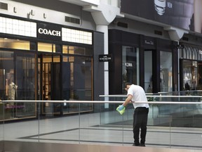 A cleaner wipes a glass panel at Toronto's Eaton Centre Shopping mall on Saturday, March 21, 2020.