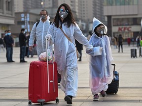 In this file photo taken on April 8, 2020 people wearing protective clothing and masks arrive at Hankou Railway Station in Wuhan.